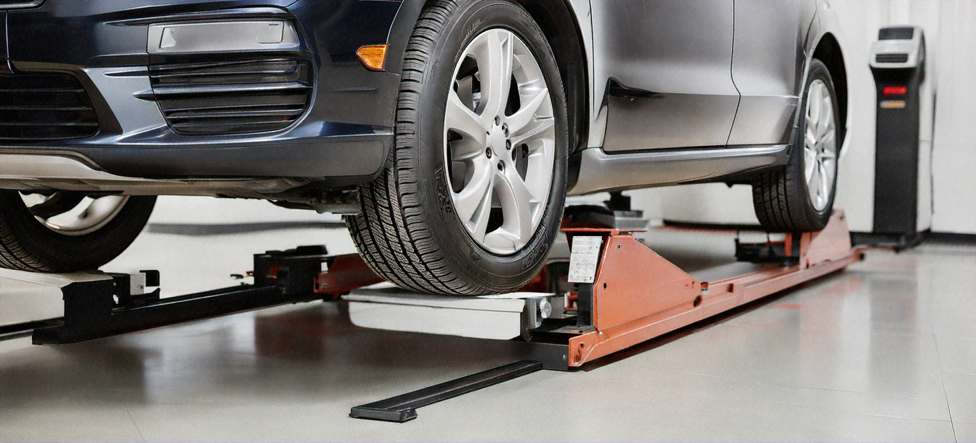 Technician performing computerized wheel alignment on a car on a lift